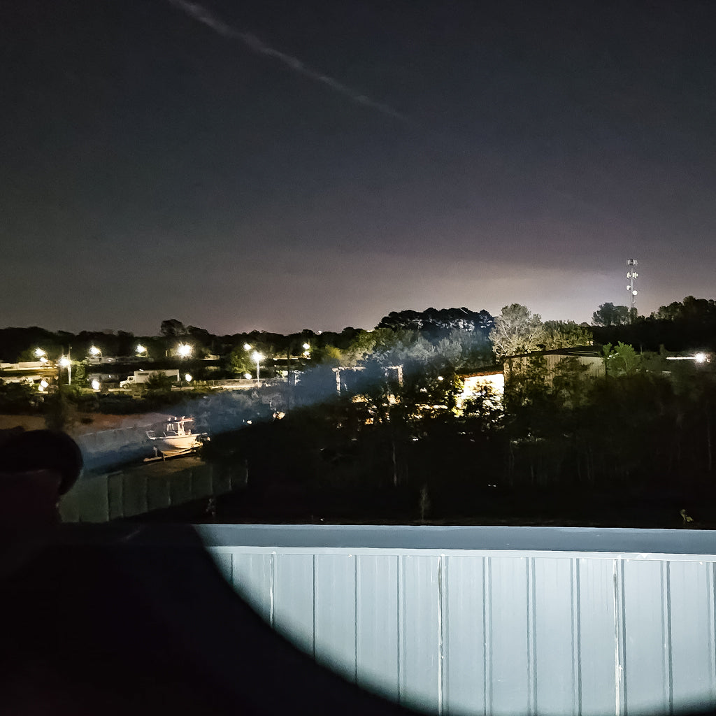 PL50X dual color long range LED flashlight white beam at night illuminating a cell phone tower